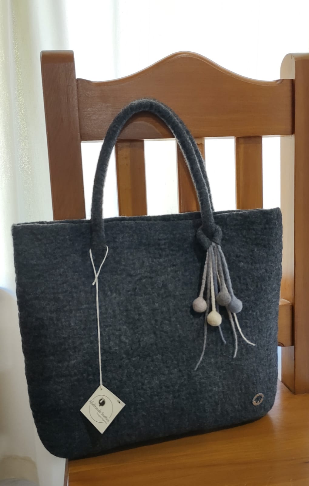 Close-up detail of felt handbag highlighting the natural Merino wool texture and artisanal finish.