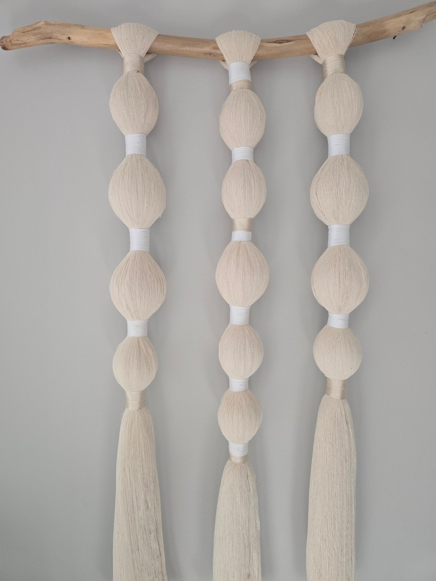 Recycled cotton macramé wall hanging displayed on a wall, minimalist boho home decor.