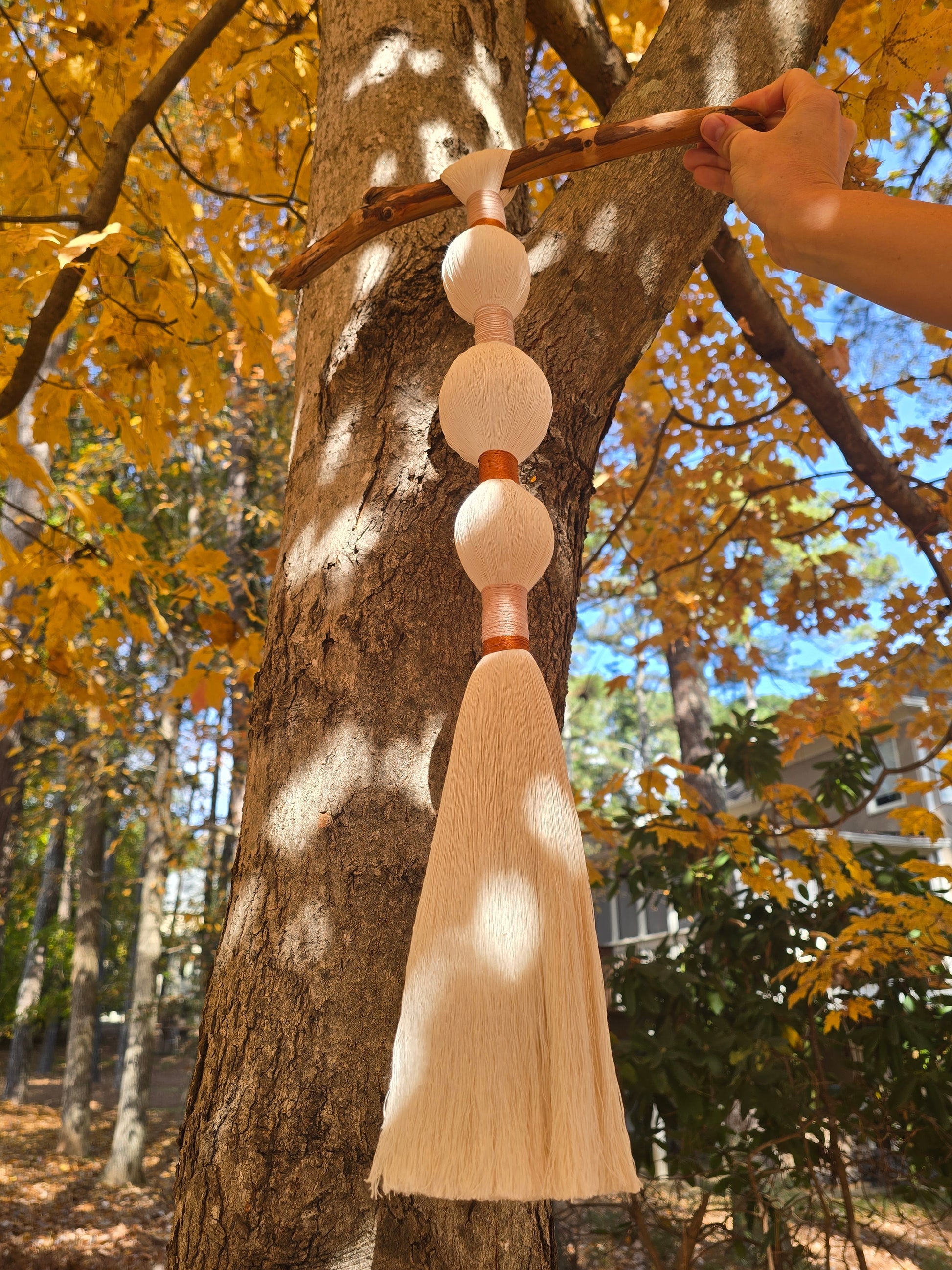 Minimal boho wall hanging in recycled cotton, displayed above a bed with neutral tones.